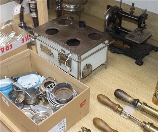 A childs tinplate cooking stove with accessories and a German-made childs sewing machine with gilt decoration